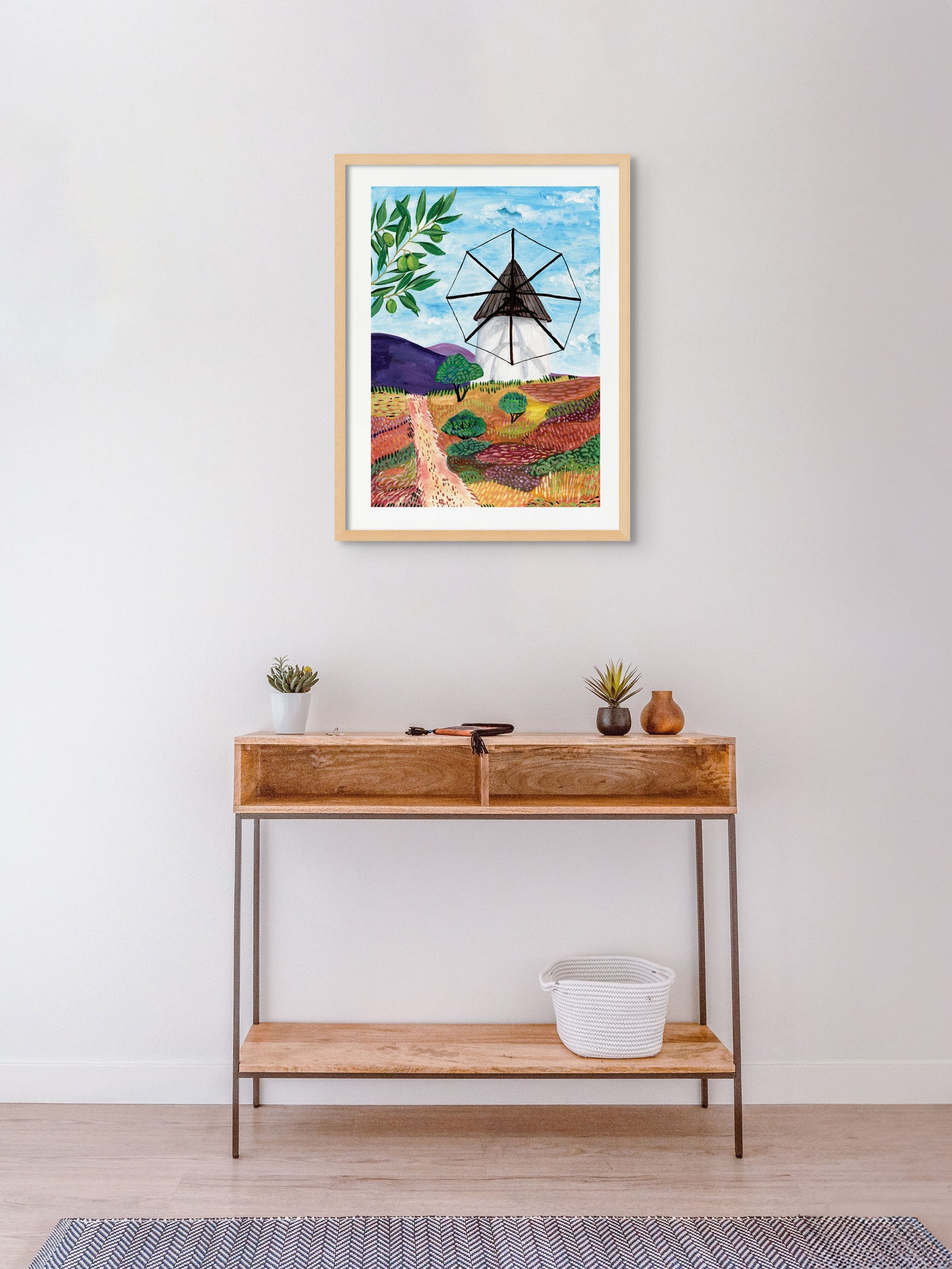A room with an art print of a windmill in Spain on the wall.