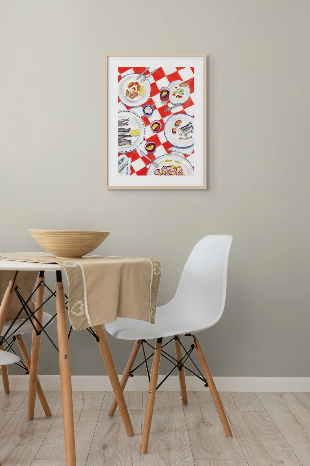 A room with an art print of a table in Spain on the wall.