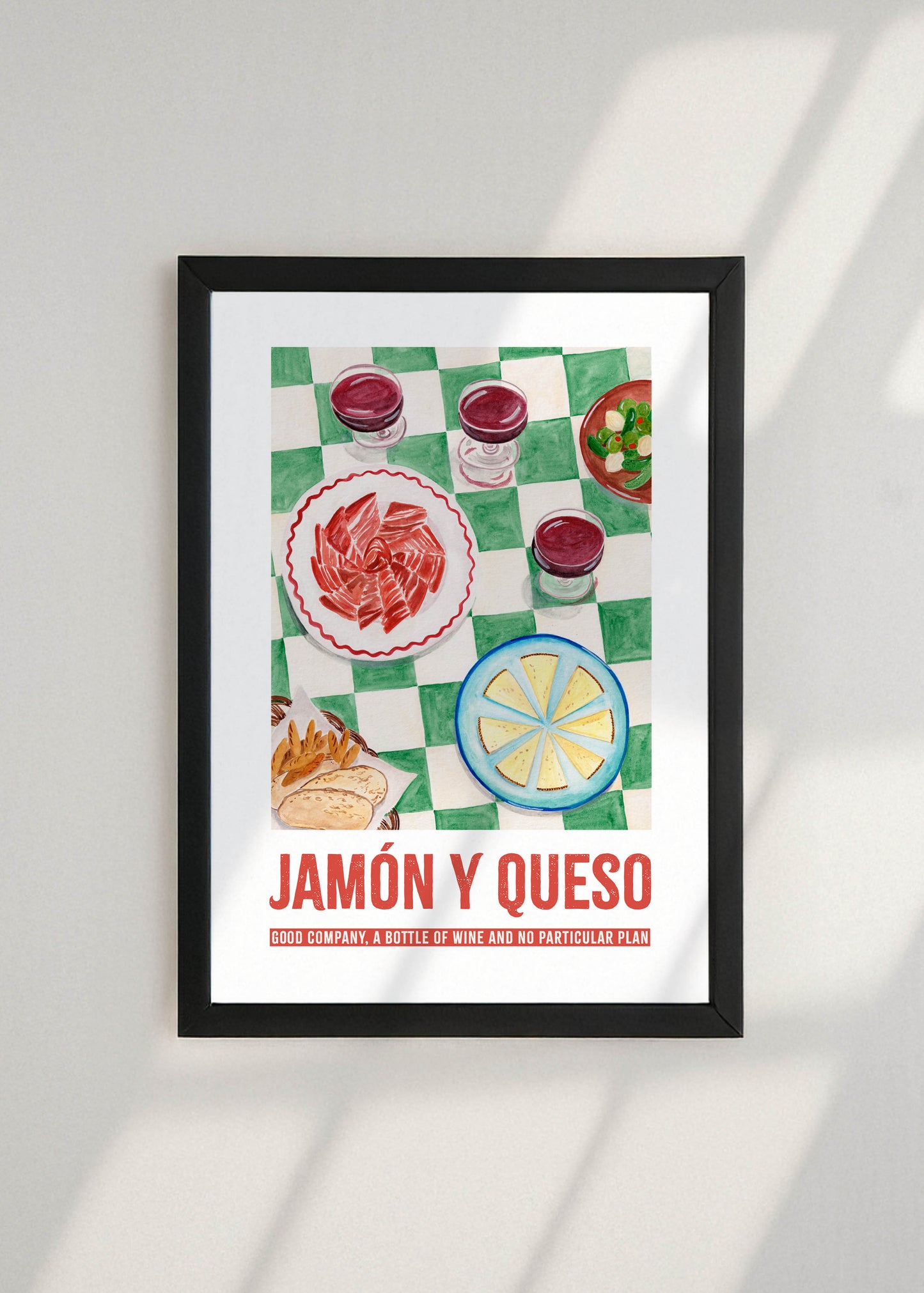 Framed artwork with an illustration of food items and 'Jamón y Queso' text on a white wall.