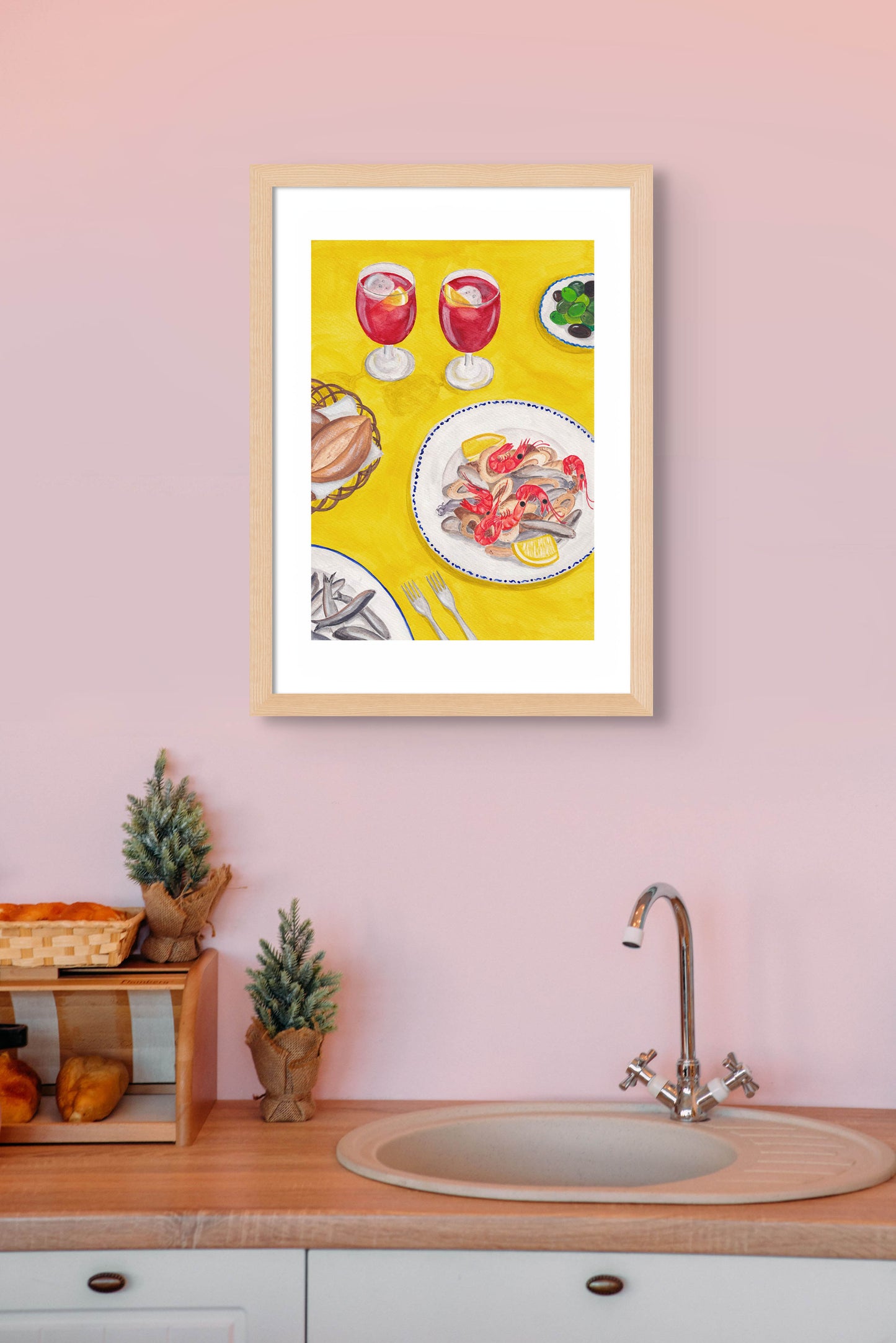 A kitchen with an art print of a still life of a table in Spain on the wall.