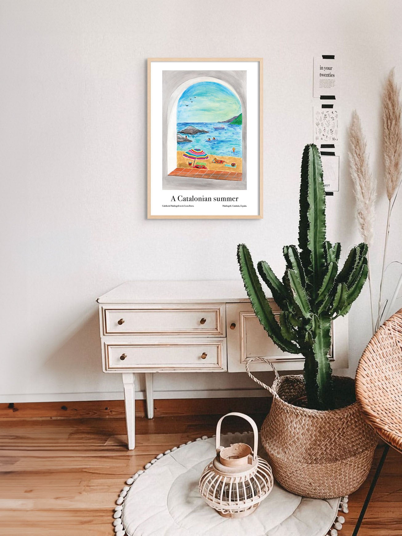 A living room with an art poster of a beach in Catalonia, Spain on the wall.