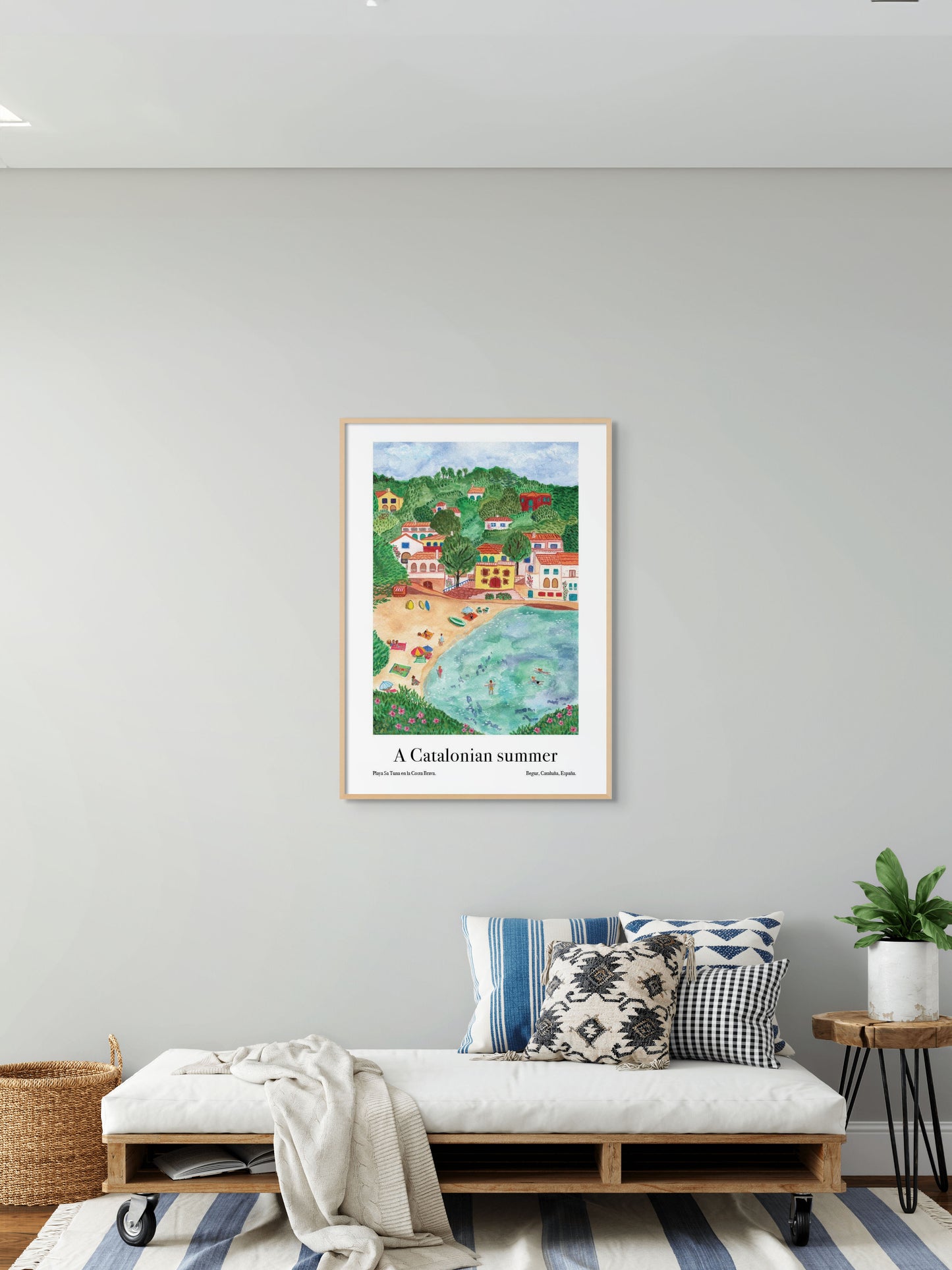 A living room with an art poster of a village and beach in Catalonia, Spain on the wall.