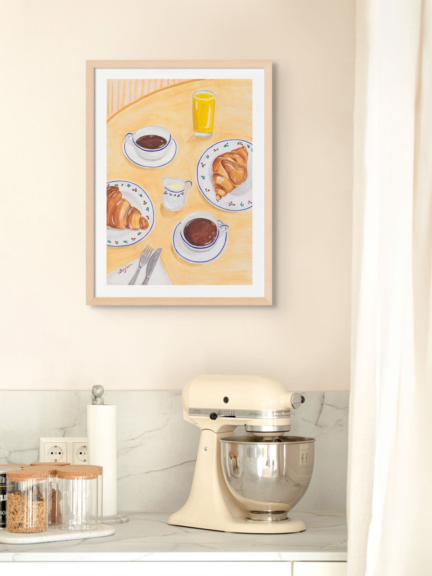 Art print of coffee and croissants in paris framed on a kitchen wall.