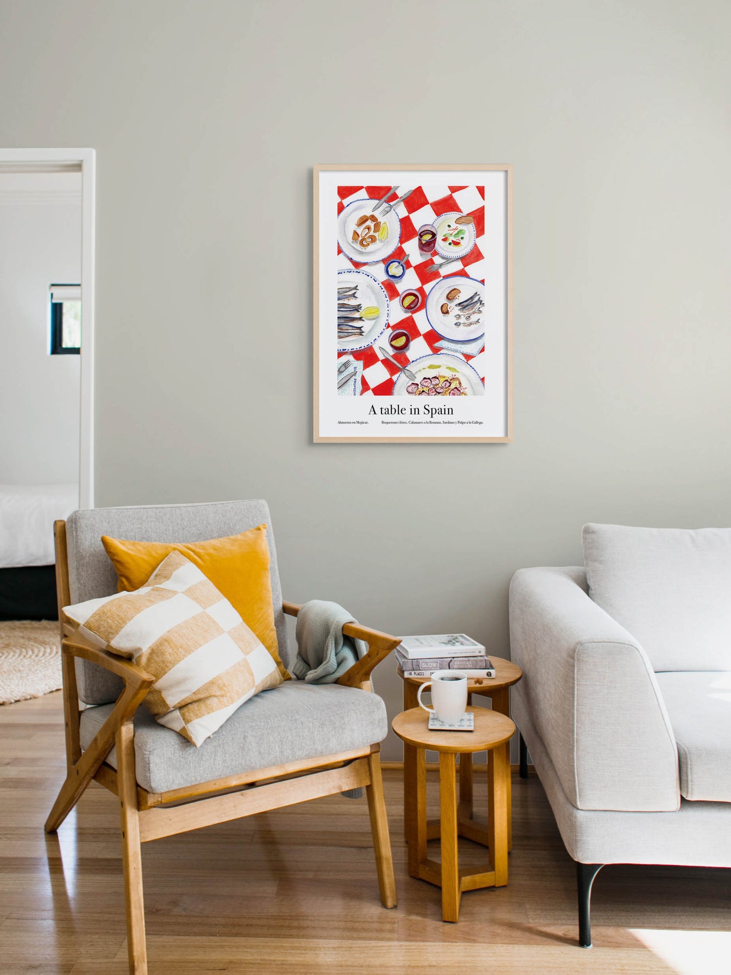A living room with an art poster of a table Spain with plates of seafood on the wall.