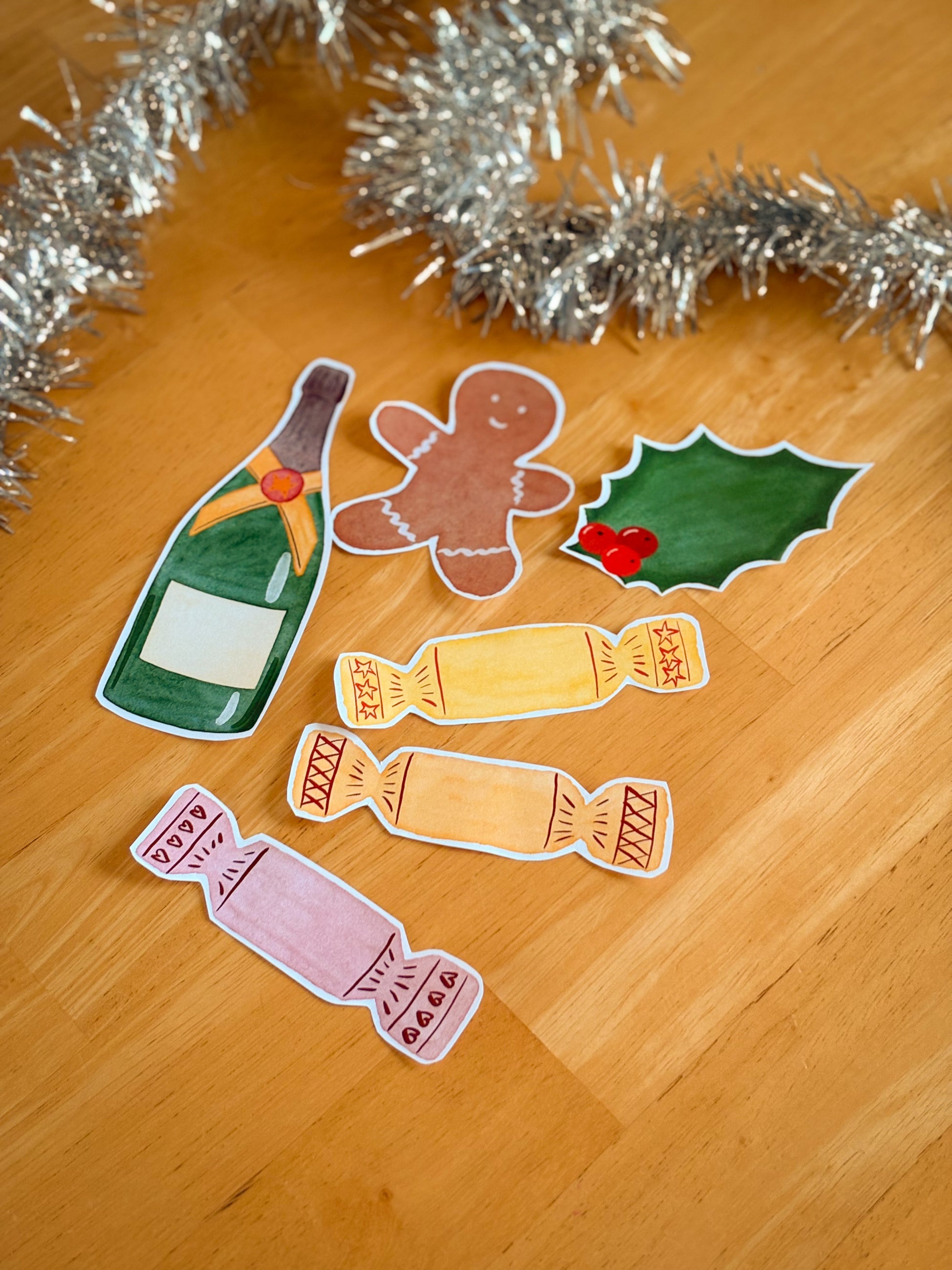Decorative elements of a bottle, gingerbread man, holly, and candies on a wooden surface with tinsel.