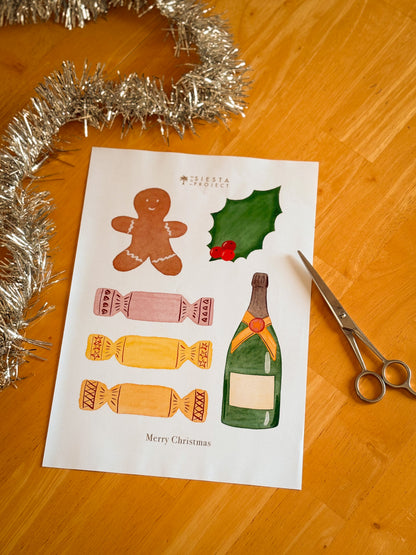 Sheet of Christmas-themed elements with a gingerbread man, holly leaf, candy, and bottle on a wooden surface with tinsel and scissors.