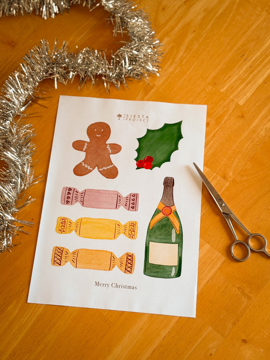 Sheet of Christmas-themed elements with a gingerbread man, holly leaf, candy, and bottle on a wooden surface with tinsel and scissors.