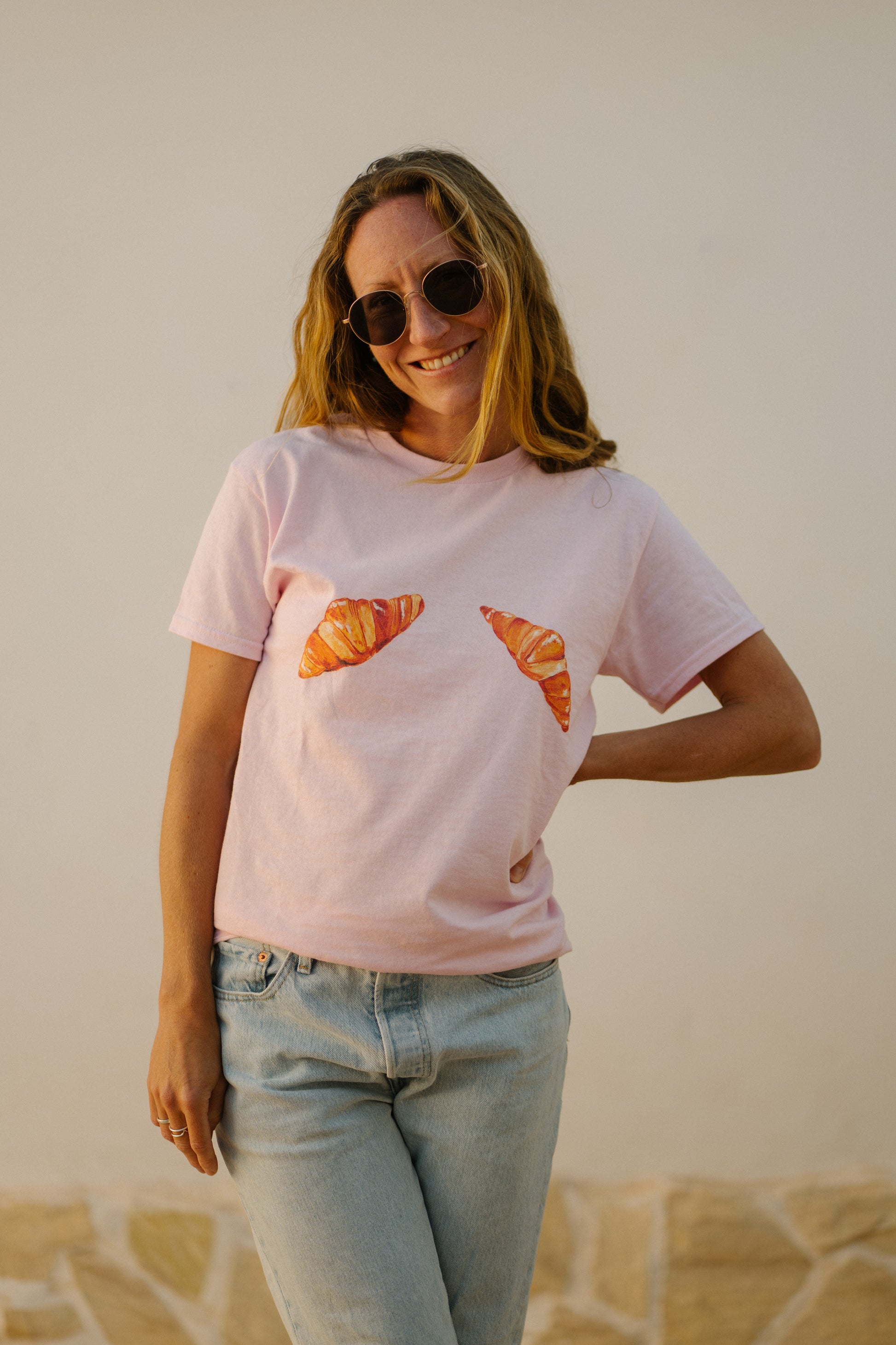 A woman wearing a pink t-shirt with hand painted croissants
