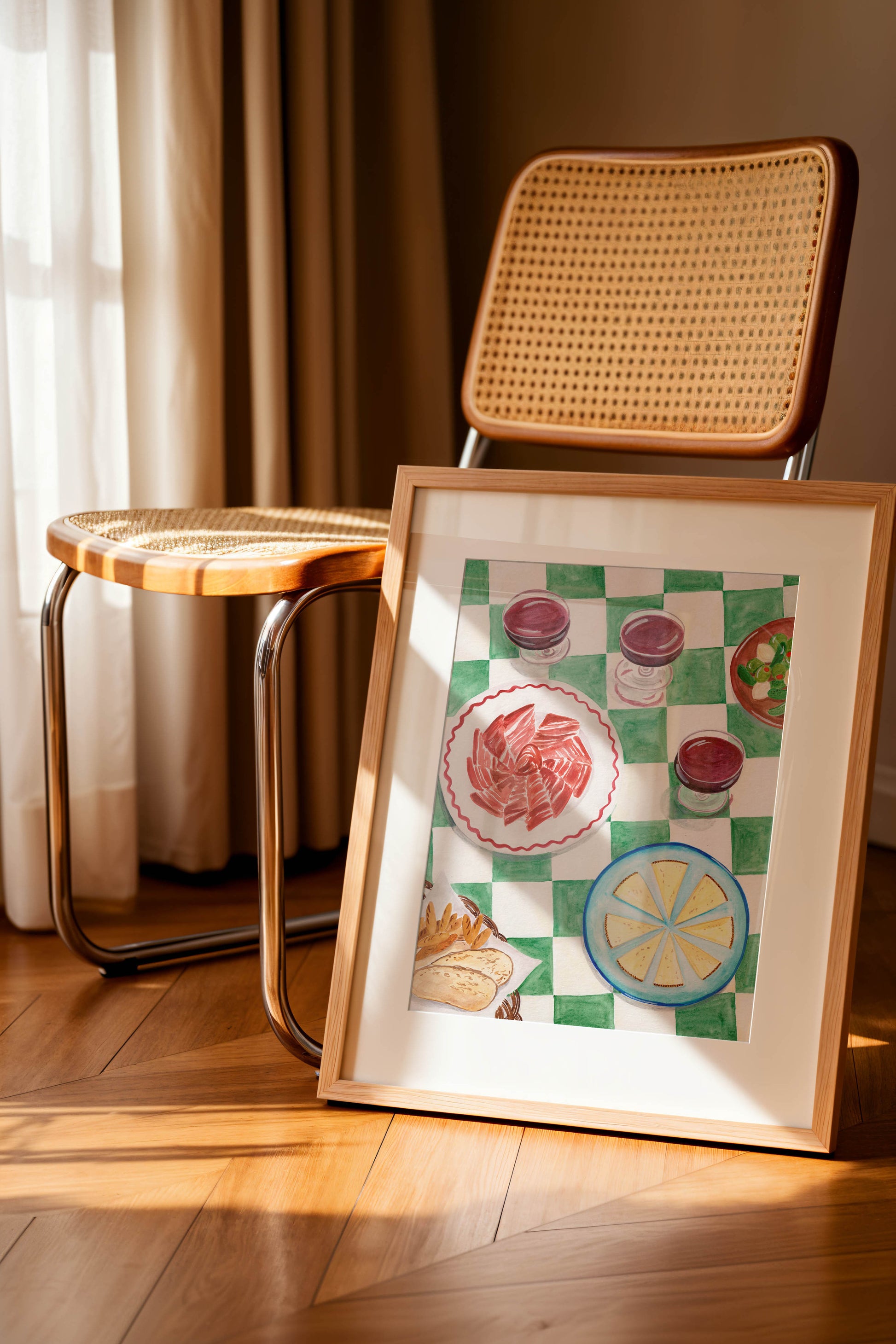 A framed art print of a table in Spain with ham and cheese and wine and a green and white checkered table cloth, perfect for kitchen decor.