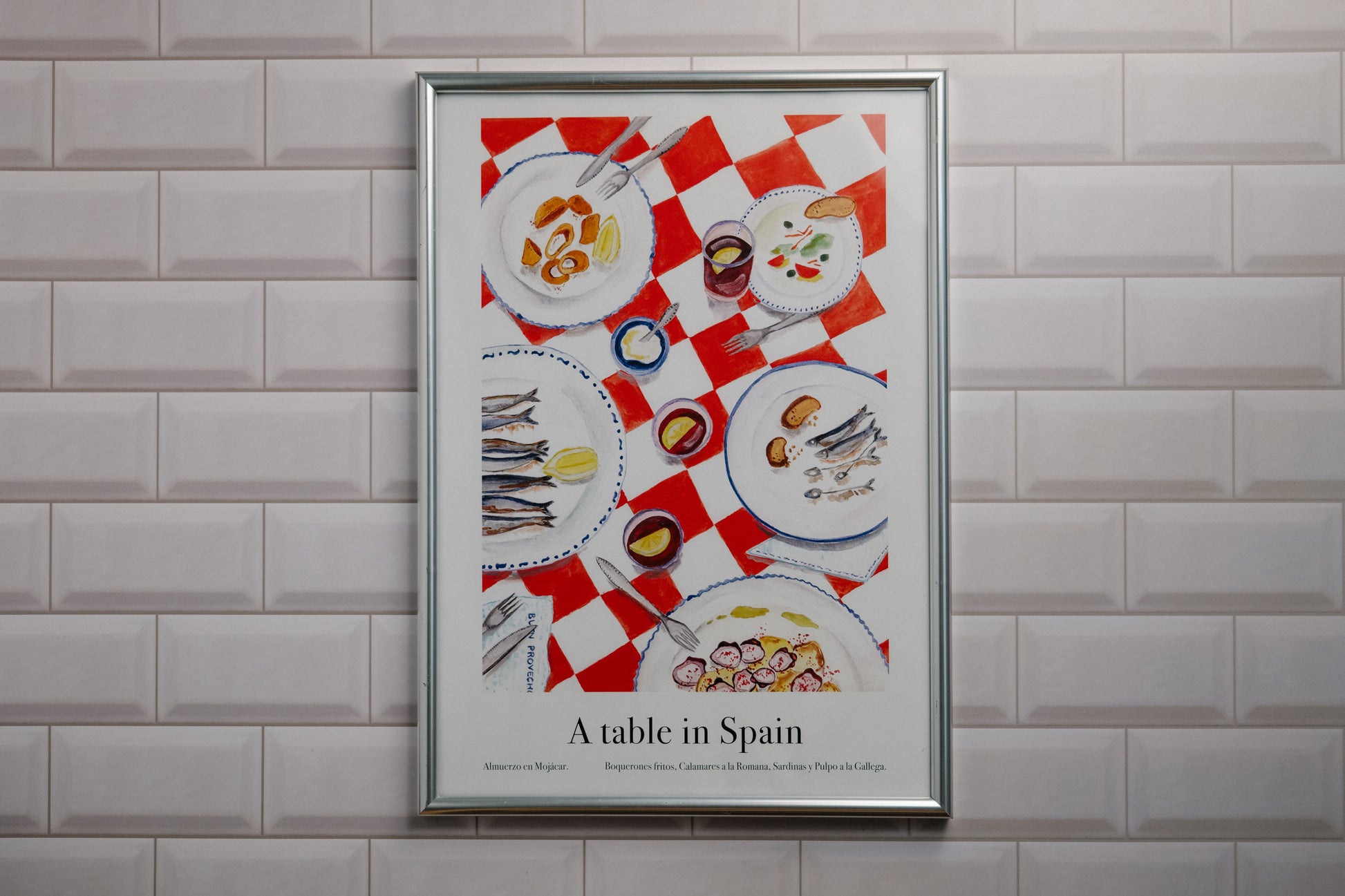Framed poster of a table setting with Spanish tapas food illustrations on a tiled wall.