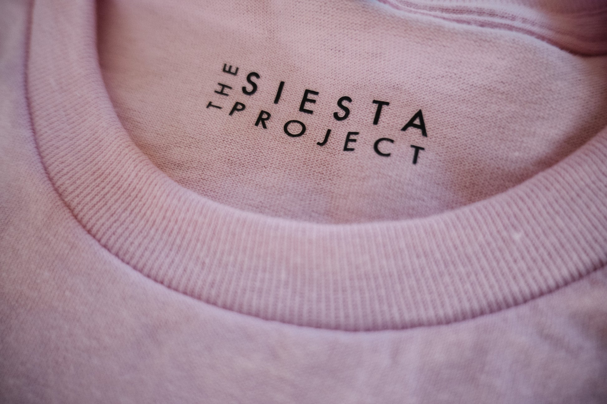A detail of a Pink t-shirt with The Siesta Project Label