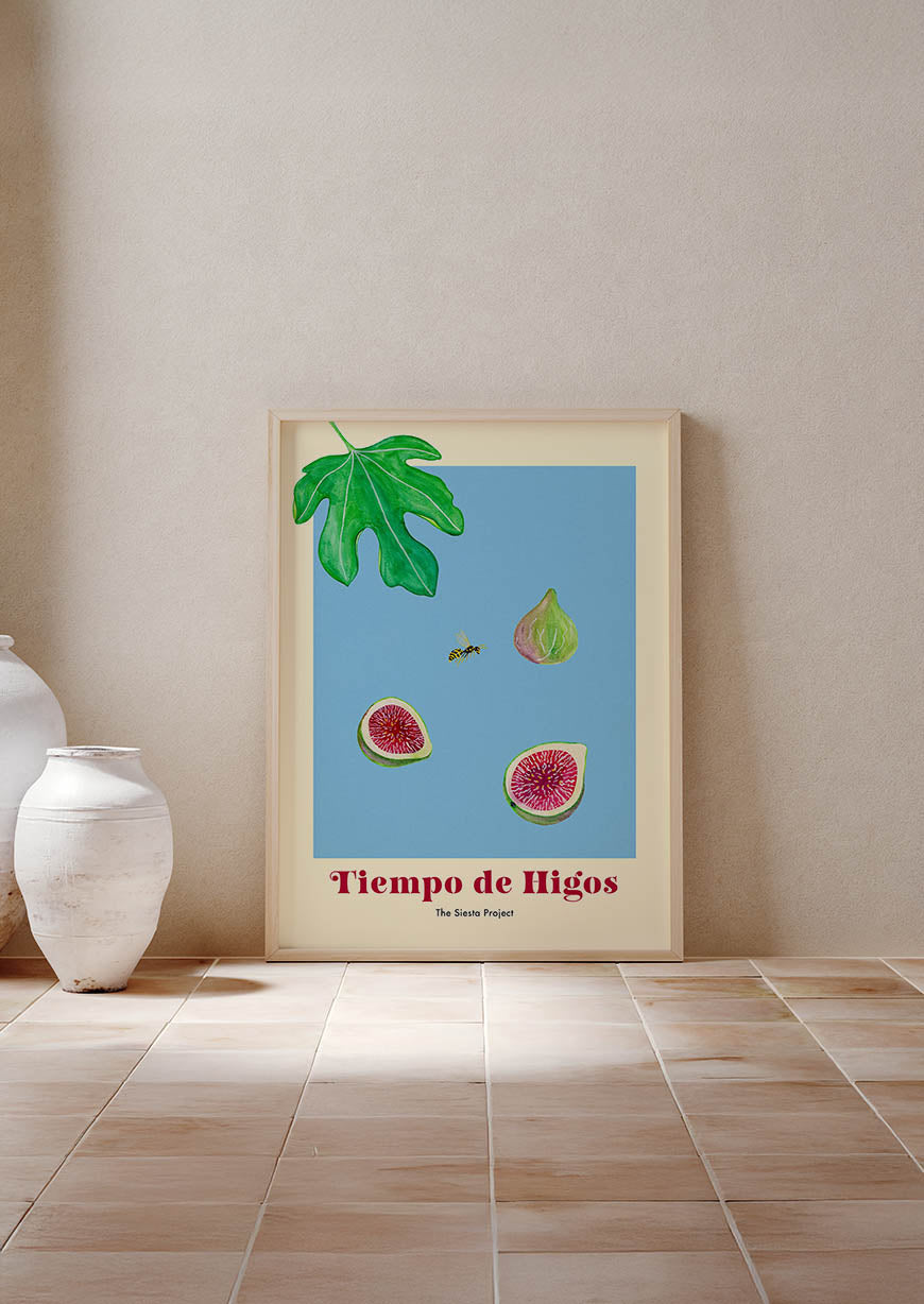 Framed artwork of figs and leaves on a wall next to a white vase.