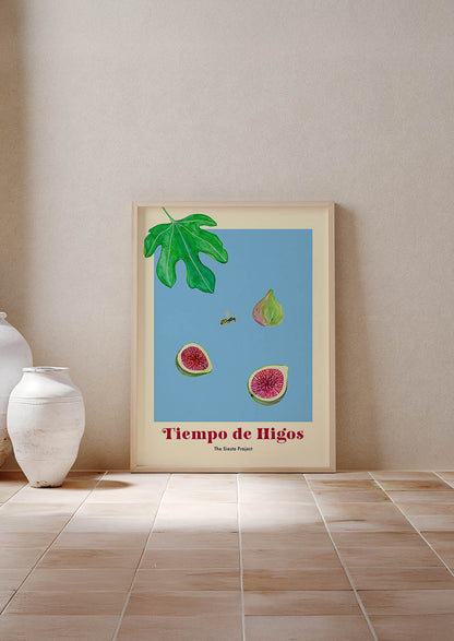 Framed artwork of figs and leaves on a wall next to a white vase.