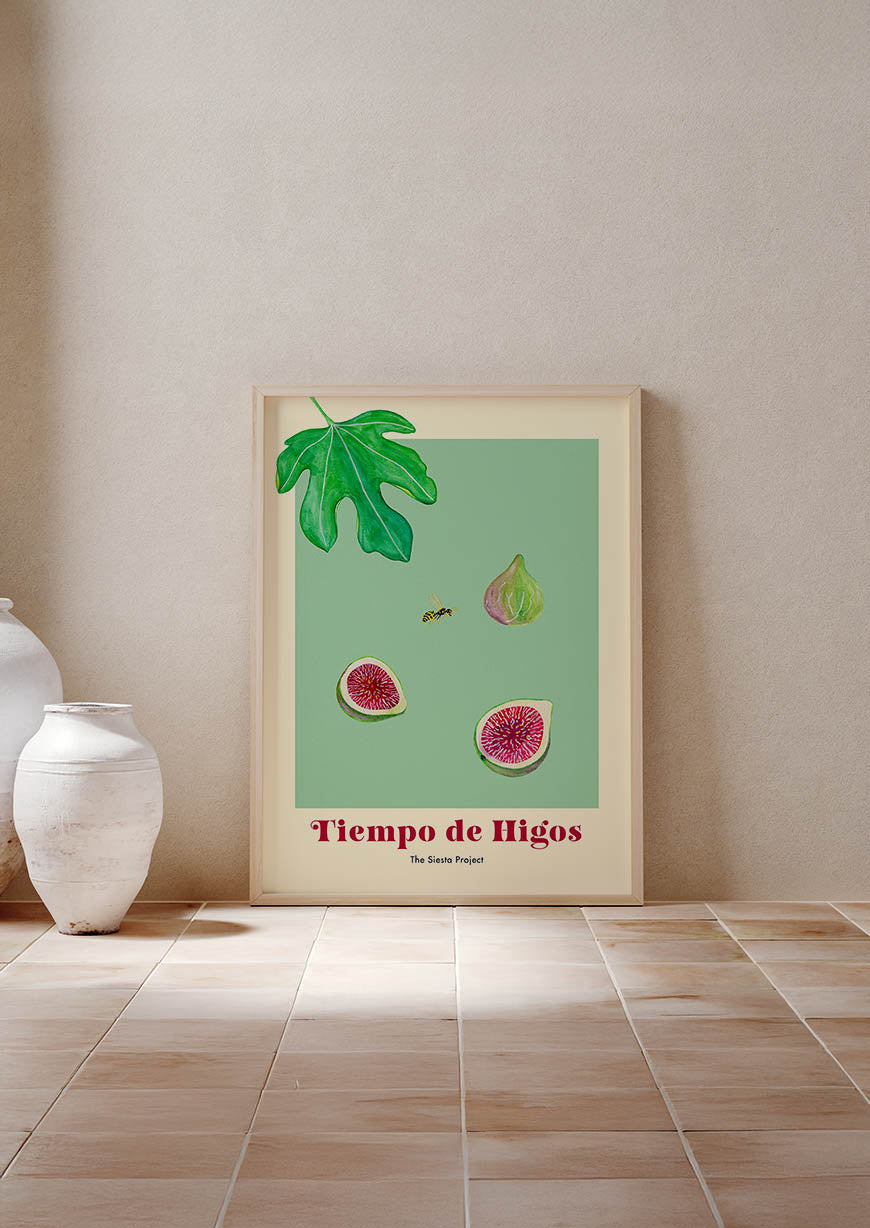 Framed artwork of figs and leaves on a green background, leaning against a beige wall.