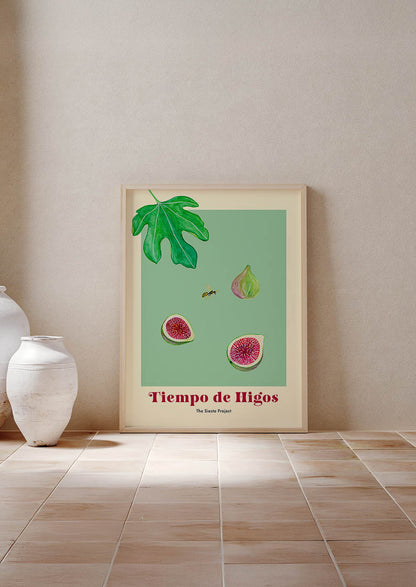 Framed artwork of figs and leaves on a green background, leaning against a beige wall.