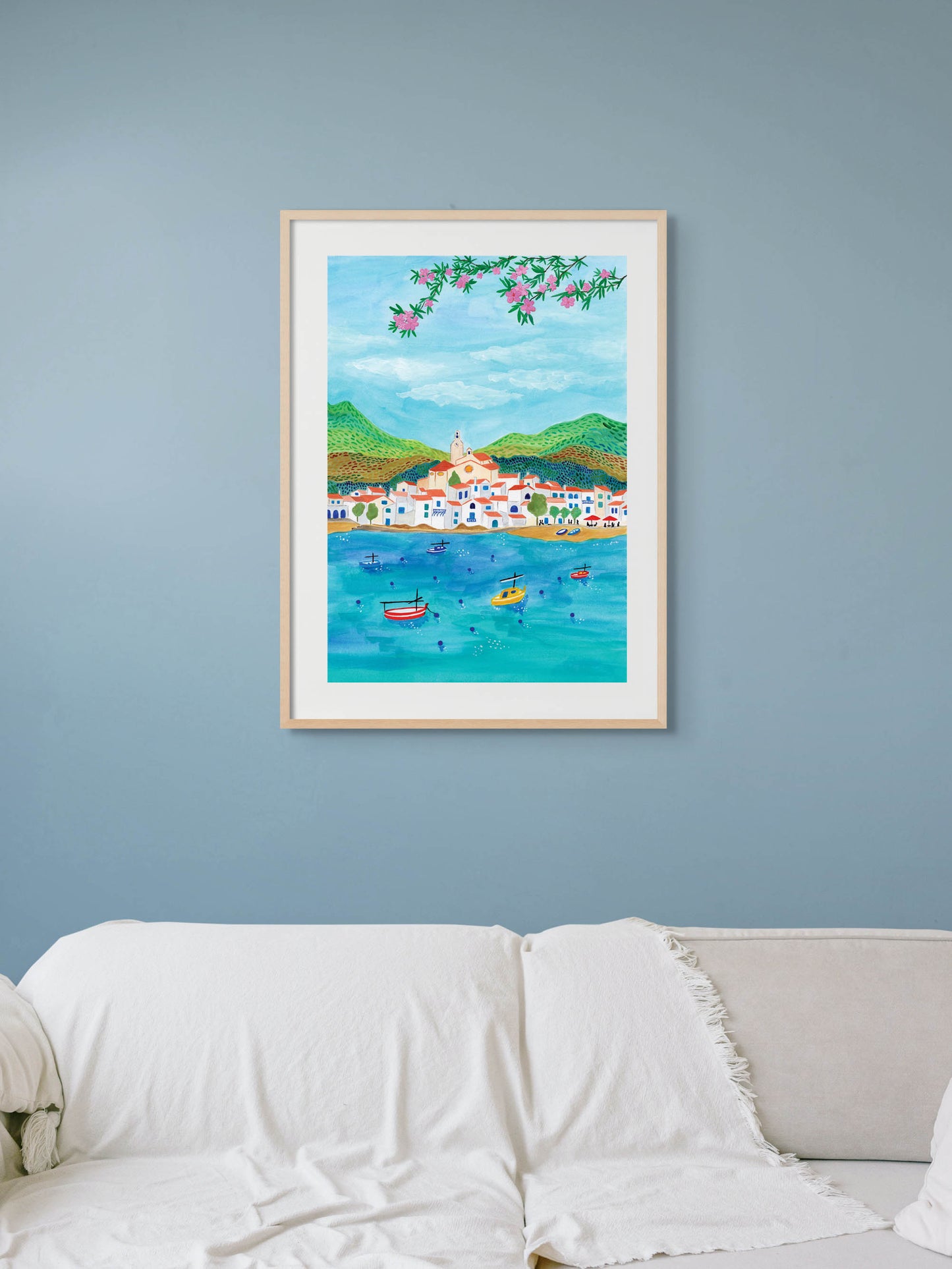 A living room with an art print on the wall of Cadaques, a village in Spain